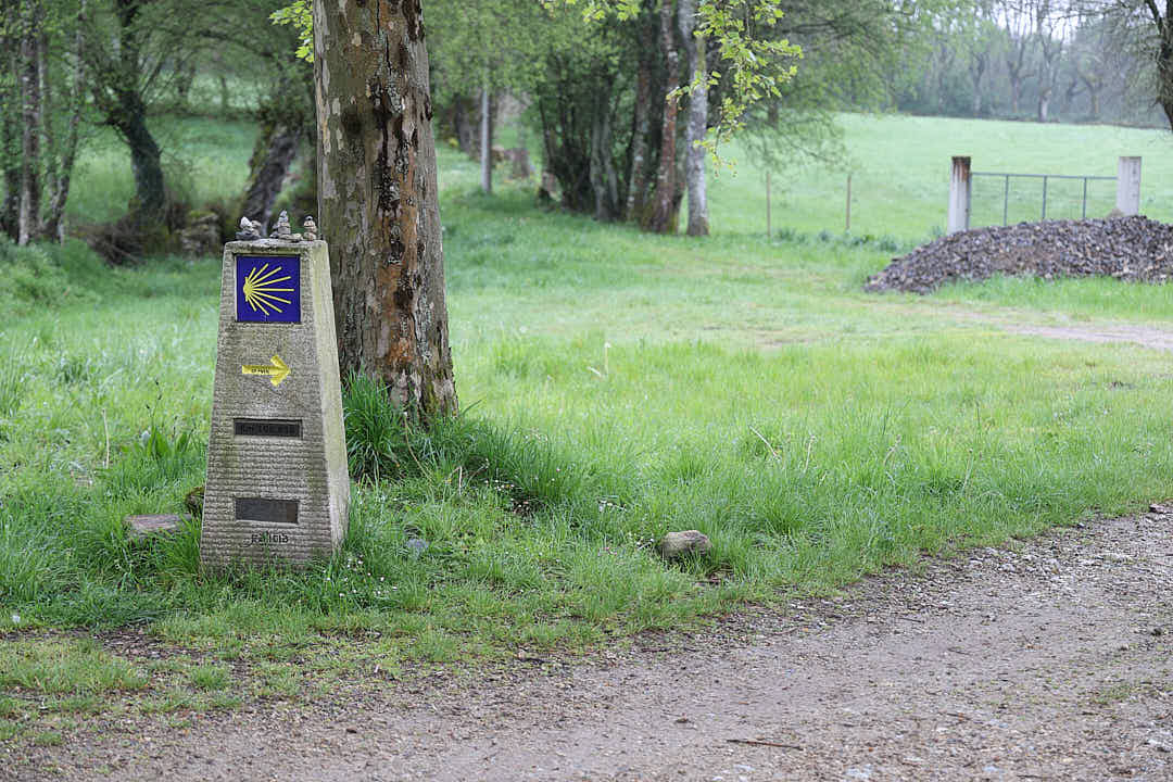 Mojón del Camino de Santiago en un camino rural de Galicia