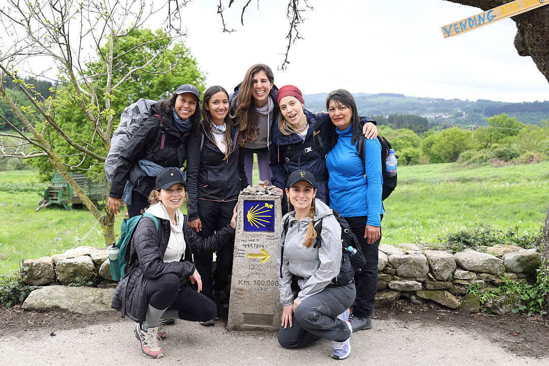 Grupo de peregrinas junto a un mojón del Camino de Santiago